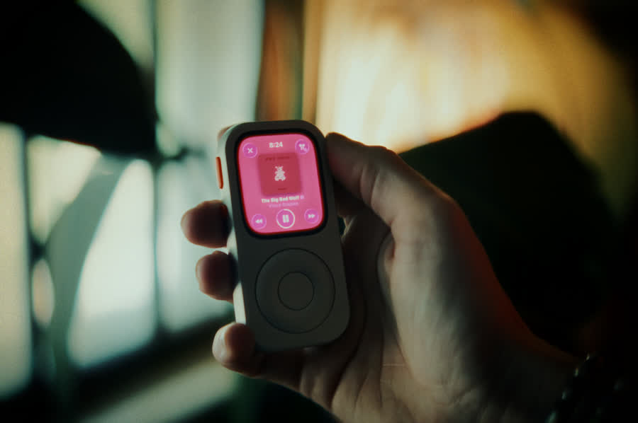 Hand holding a front-facing RePod C1 with music playing on Apple Watch